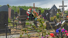 City Cemetery With Fresh Graves, Wooden And Stone Gravestones, Metal Crosses. City Geaveyard. Defocused Foreground.