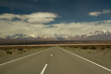 Wall Mural - Traveling along the asphalt highway across the arid desert and into the Andes cordillera, under a beautiful blue sky with clouds.