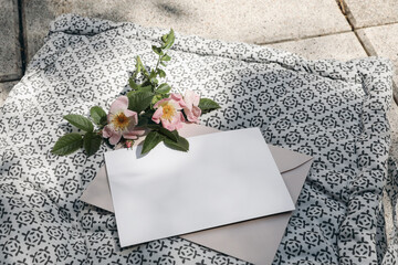 Wall Mural - Summer stationery mock-up. Blank paper card invitation, craft envelope and blooming dog rose in sunlight. Patterned cushion, seater. Summer branding photo, web banner. Top view, blurred background.