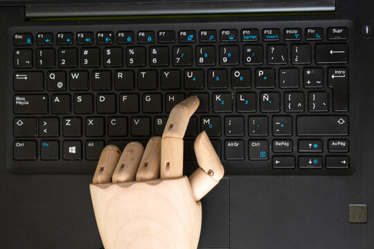 Wooden mannequin hand typing on laptop – AI and technology concept