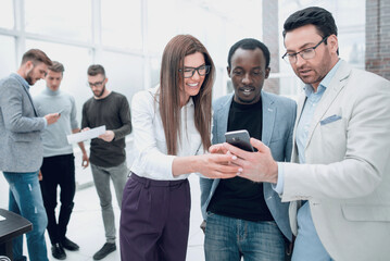 Wall Mural - smiling colleagues looking at the smartphone screen