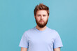 Portrait of confident strict bearded man looking directly at camera with serious attentive face, listening attentively, unsmiling determined male. Indoor studio shot isolated on blue background.