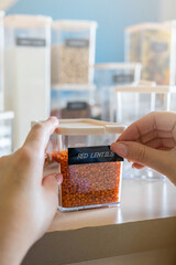 Wall Mural - Closeup female hands applying printing sticker with name red lentils on transparent plastic case box