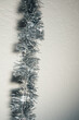 Sparkly silver tinsel against white wall, background