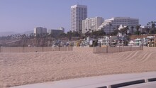 Gimbal Shot Of Beach Bike Path In Santa Monica, CA.  Showing Sandy Beach In Foreground And Popular Hotels In The Distance.