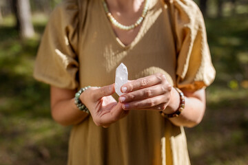 occult science and supernatural concept - close up of woman or witch with semiprecious crystal or gemstone performing magic ritual in forest