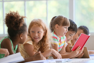 Poster - Cute little children reading books on floor in classroom