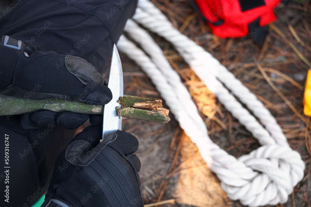 Male tourist making wooden stake in forest, closeup