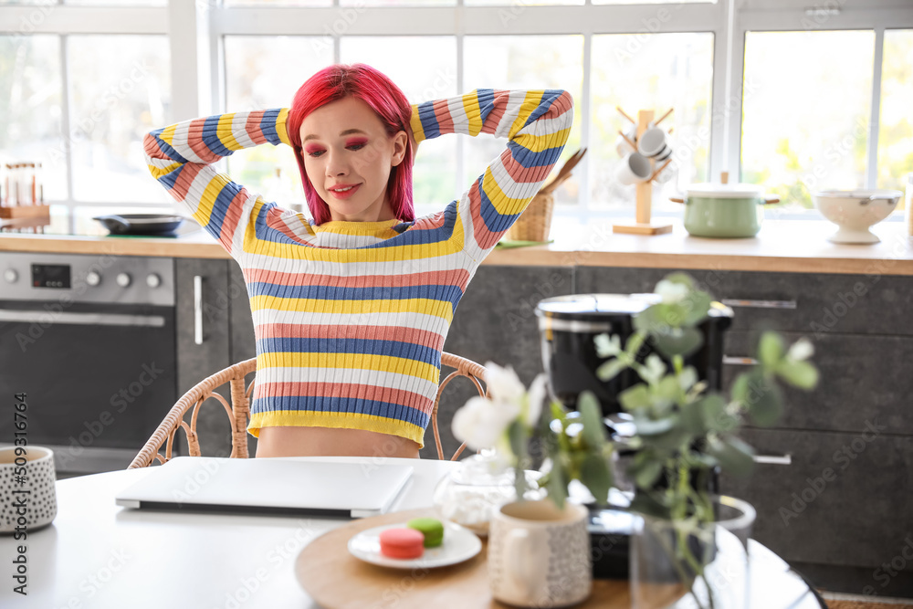 Beautiful woman with bright hair relaxing at table in kitchen