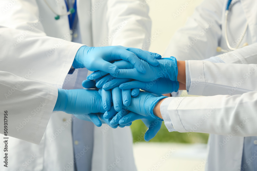 Group of doctors putting hands together in clinic
