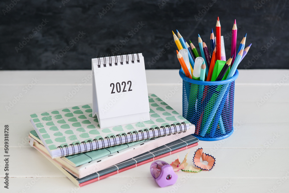 Different stationery on table near black wall