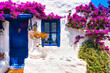 Charming typical floral streets of Greek islands with whitewashed houses and blue doors