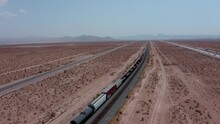 Aerial Of A Freight Train Travelling Through The Arizona Desert. Freight Supply Train Aerial. Ground Transportation In Rural America. Texas Desert Train. 