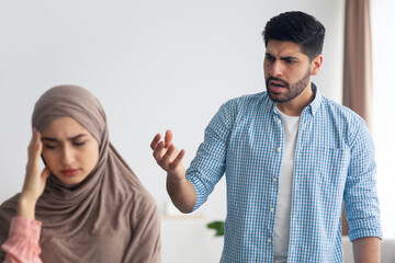 Wall Mural - Aggressive Islamic Husband Shouting At Victimized Wife Standing At Home