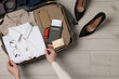 Woman packing suitcase on wooden floor, top view with space for text. Business trip planning