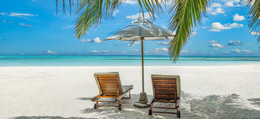 Beautiful tropical island, two chairs, umbrella under palm tree leaves, paradise sea sand sky. Summer travel landscape, vacation beach scenic, idyllic exotic nature closeup of recreation, relaxation. 