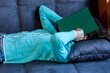 © Beliakina Ekaterina - The girl covered her face with a book while lying on the sofa
