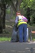 © vladimir subbotin - A female utility worker cleans garbage in the alley of the city park