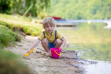 Poster - Little toddler child, cute boy, playing with toys in the sand on a lake