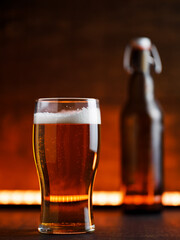 Wall Mural - pint glass of light beer on a wooden background. Bottle with a bugle stopper