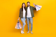 Full Body Photo Of Lovely Couple Hold Shopping Bags With Stylish Clothes Isolated On Yellow Color Background