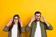 Leinwandbild Motiv Photo of positive intelligent woman and man wear eyeglasses look up see promotion ad isolated on yellow color background