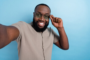 Wall Mural - Portrait of positive nice person take selfie arm touch glasses toothy smile isolated on blue color background