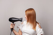 © millaf (Nemchinova) - Portrait of beautiful woman drying her red hair with dryer over gray background