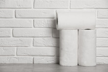 Rolls Of White Paper Towels On Grey Table Near Brick Wall. Space For Text