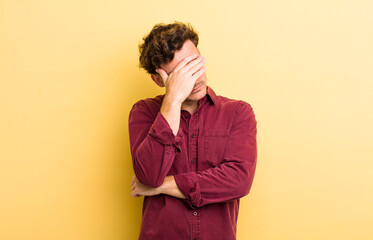 Wall Mural - young handsome man looking stressed, ashamed or upset, with a headache, covering face with hand