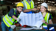 © atitaph - Male and female engineers chat with factory workers as they use machine drawings, planning for industrial maintenance