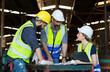 © atitaph - Male and female engineers chat with factory workers as they use machine drawings, planning for industrial maintenance