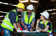 © atitaph - Male and female engineers chat with factory workers as they use machine drawings, planning for industrial maintenance