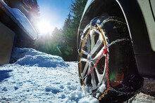 Car Wheel With Winter Chains For Icy Road Over Sunny Background