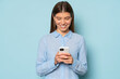 © Damir Khabirov - Cute smiling girl reading corporate online chat on phone isolated over blue background