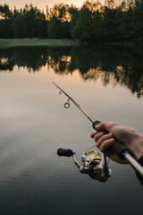 Wall Mural - Fishing day. Fishing for pike, and perch from a lake, river or pond. Background wild nature. Fisherman with rod, spinning reel catches fish from a pier or boat. Article about concept of rural getaway.