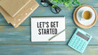 LET'S GET STARTED text concept write on notebook with office tools on wooden background