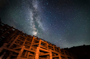 Wall Mural - Night landscape photography. Old check dam in the starry night.  Bright milkyway galaxy.