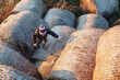 © Linas T - The little boy, in the autumn evening, in the sunset light, climbs up the hay rolls. Photographed from above