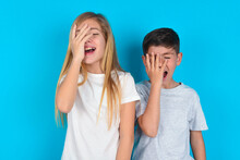 Charismatic Carefree Joyful Two Kids Boy And Girl Standing Over Blue Studio Background Likes Laugh Out Loud Not Hiding Emotions Giggling Hear Funny Hilarious Joke Chuckling Facepalm.