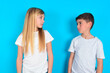 © Jihan - Side view of young happy smiling two kids boy and girl standing over blue studio background