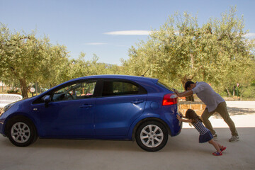 Wall Mural - Nice image of a man who with his daughter push their car after having had a breakdown and running out of petrol. Reference to the current expensive fuel