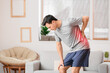 © Pixel-Shot - Young man suffering from back pain at home