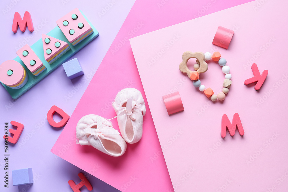 Baby booties with educational toys on color background