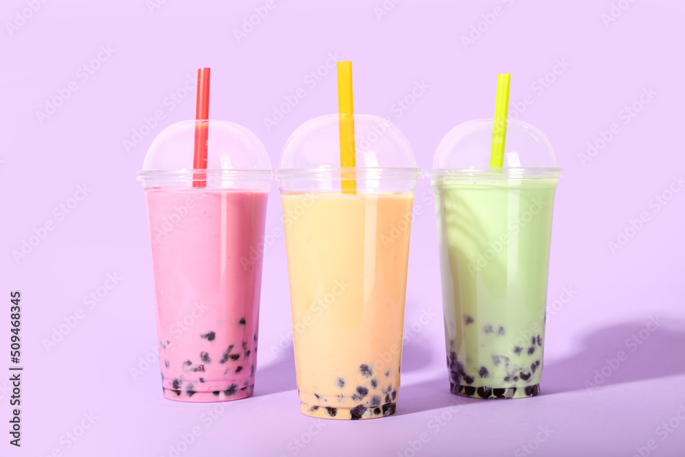 Plastic cups of tasty bubble tea on purple background
