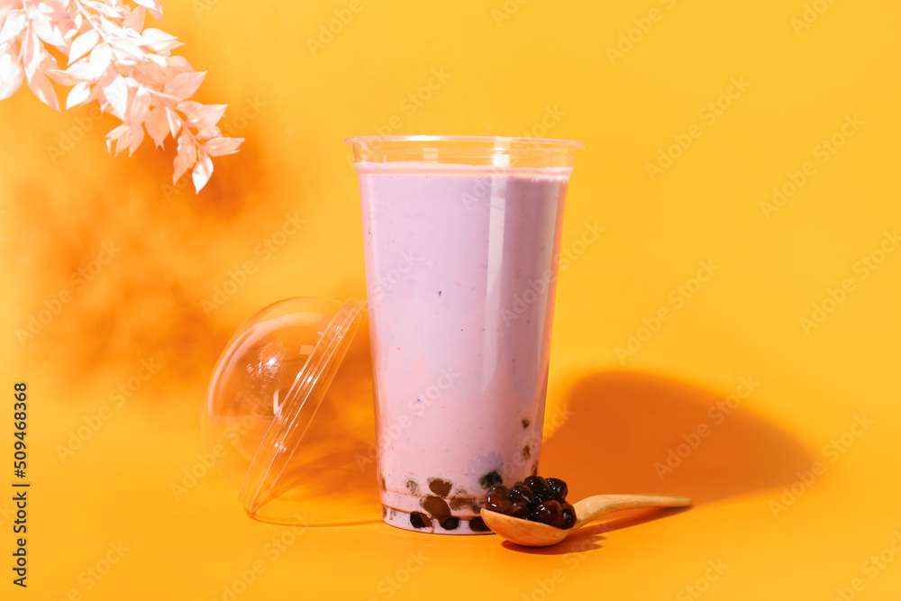 Plastic cup of tasty bubble tea on orange background