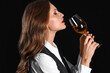 Beautiful female sommelier with wine on black background