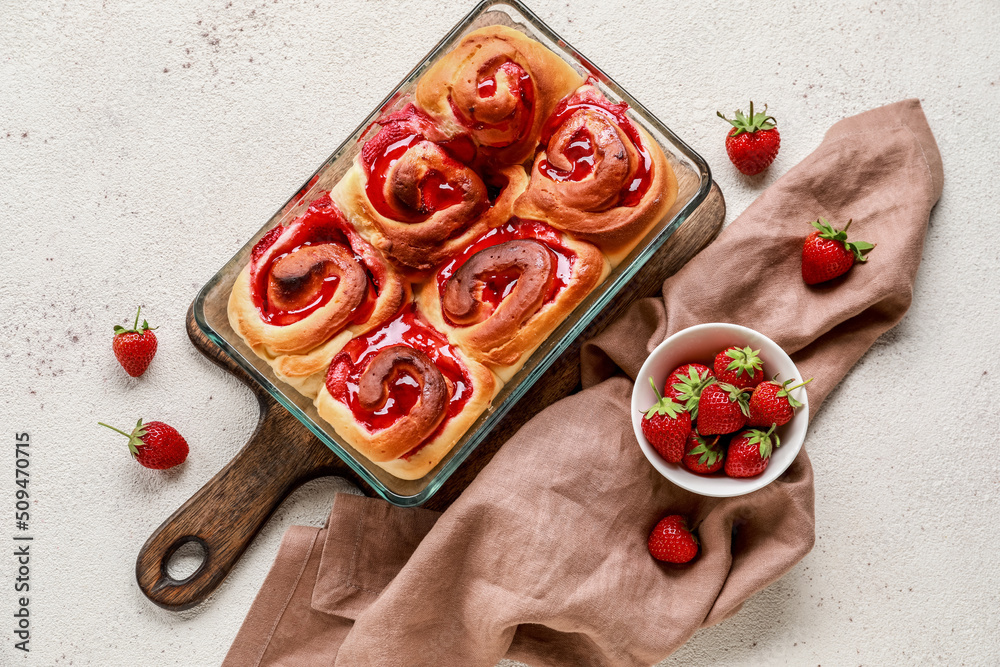 Baking dish with strawberry cinnamon rolls on white background