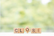 Close word is written on wooden cubes on a green summer background Closeup of wooden elements