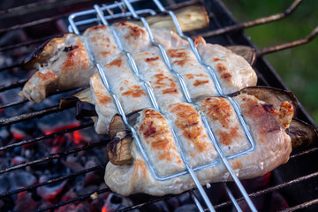 Grilled bacon-wrapped chicken tenders with lemon and rosemary on the grill wih grilled vegetables - peppers, and and eggplant